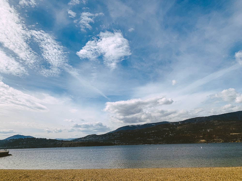 a body of water surrounded by mountains and clouds