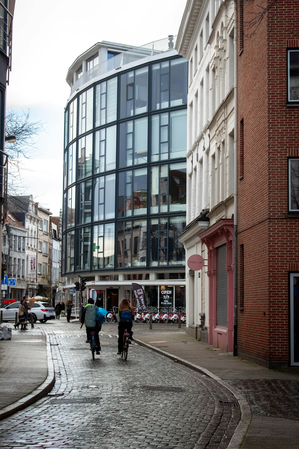 a group of people riding bikes down a street next to tall buildings