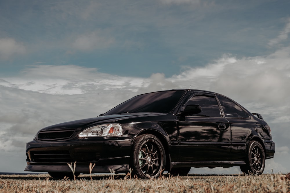 a black car is parked in a field