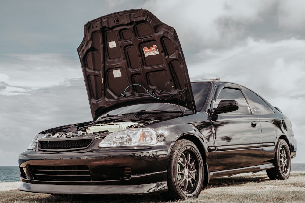 a car with its hood open on the beach