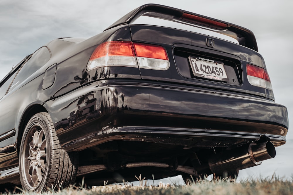 a black car parked in a grassy field