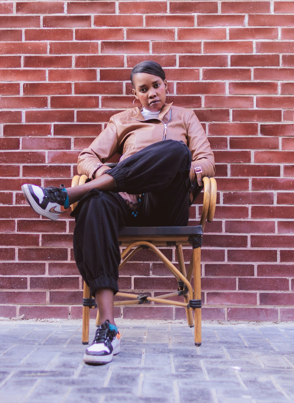 a woman sitting in a chair with a brick wall behind her