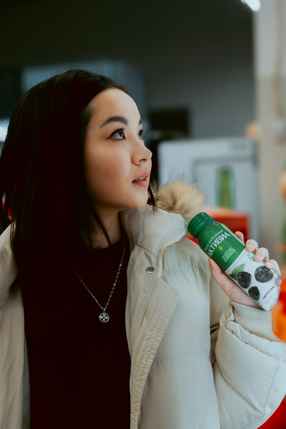 a woman in a white jacket is holding a bottle