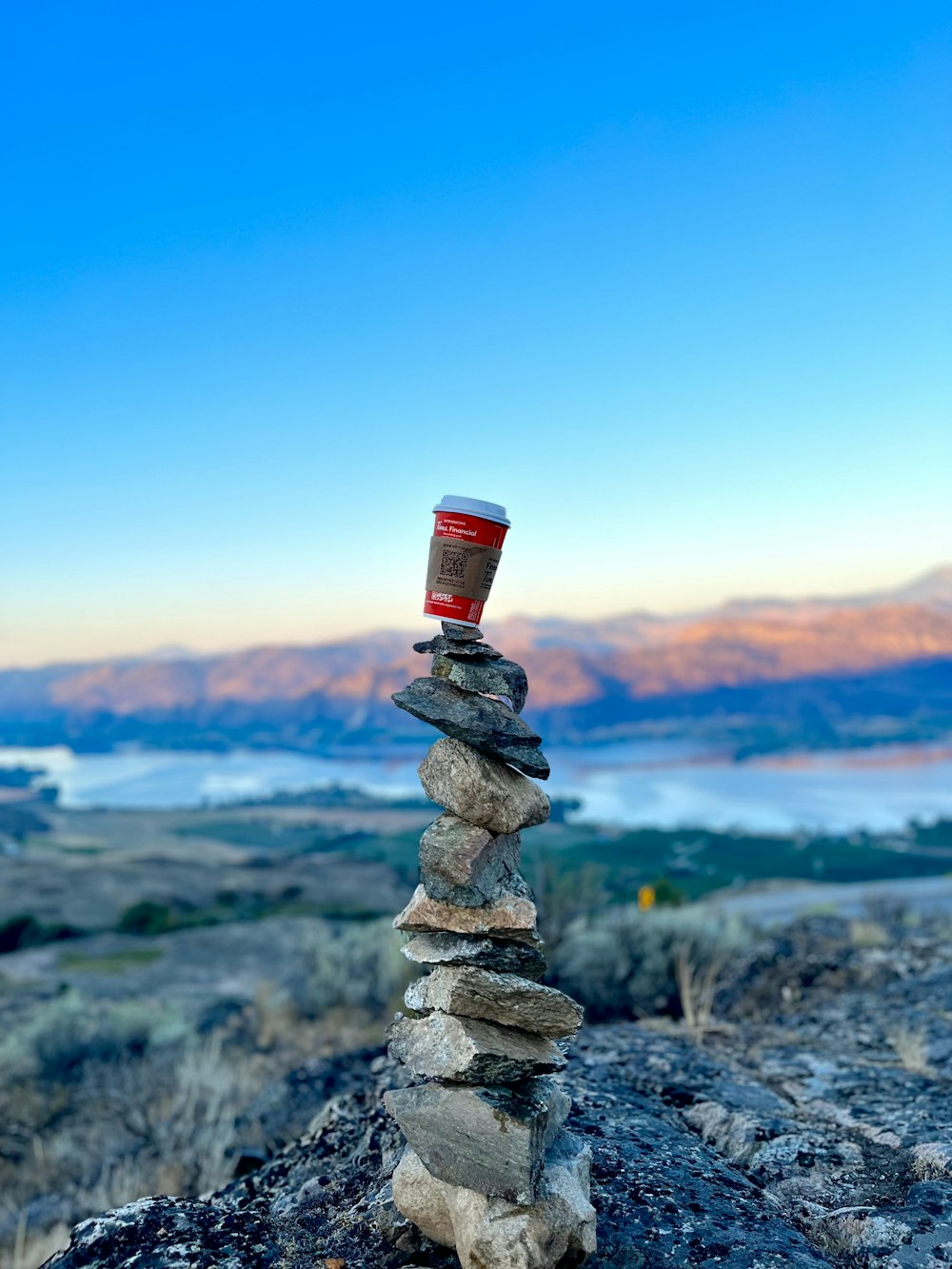 a cup of coffee sitting on top of a pile of rocks