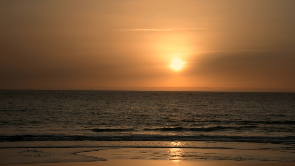 the sun is setting over the ocean on the beach