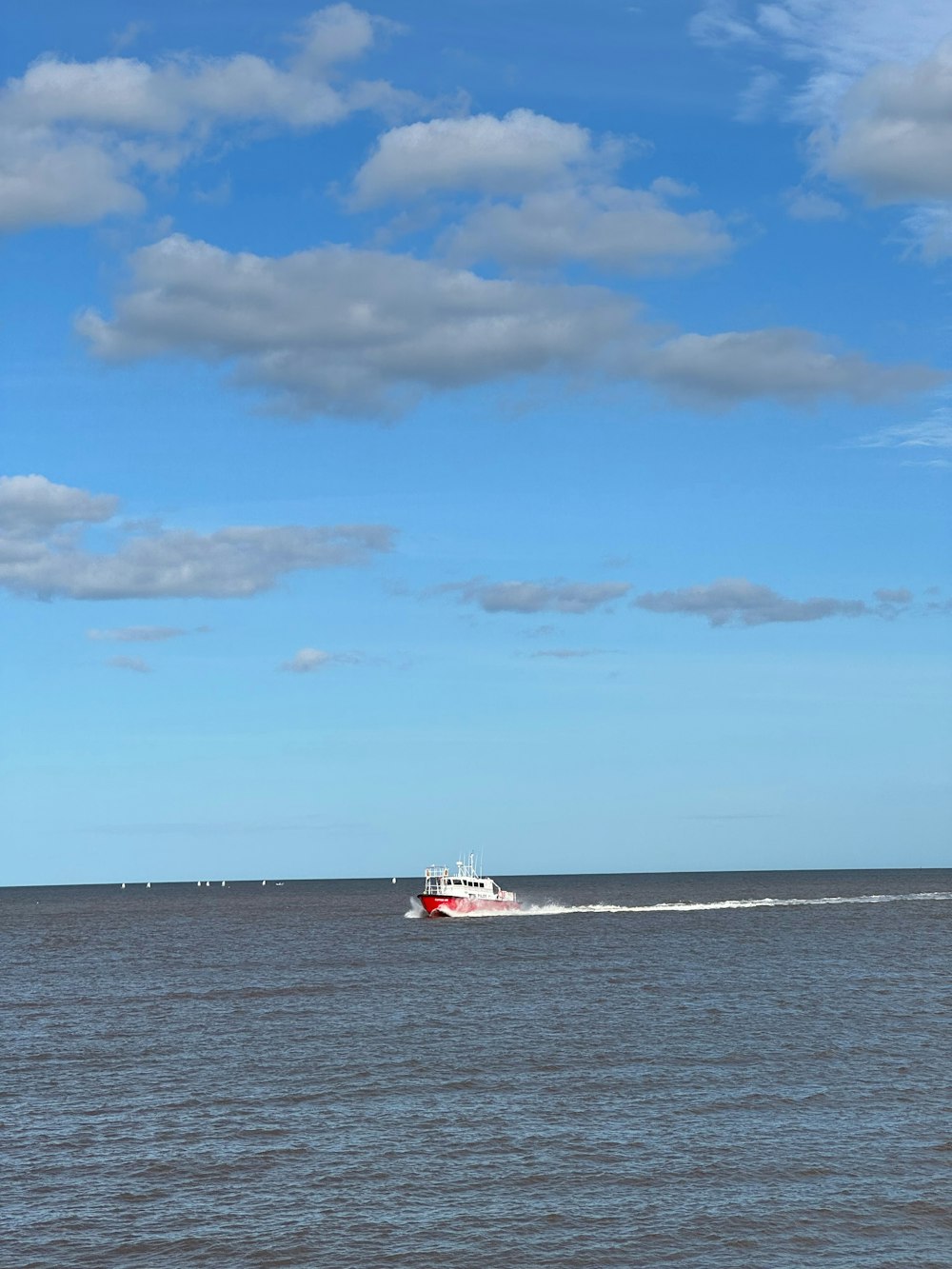 a red and white boat traveling across a large body of water