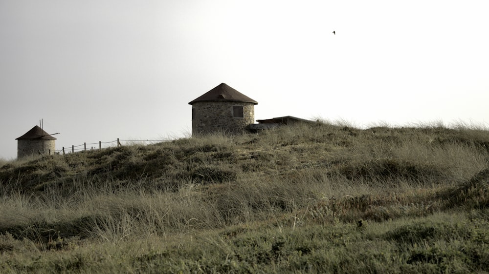 a grassy hill with two small buildings on top of it