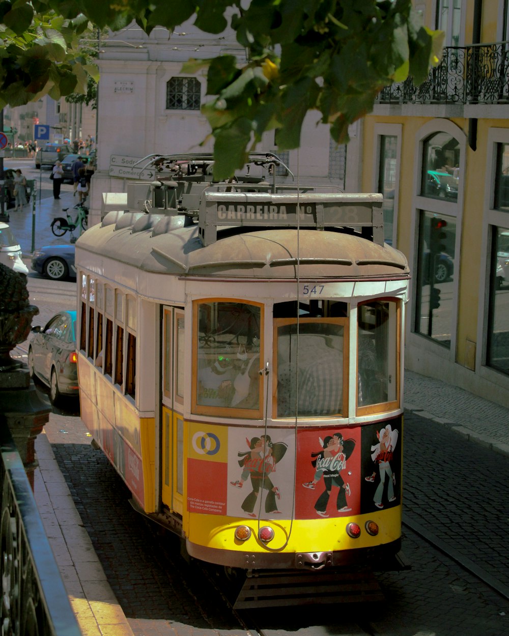 a yellow and red trolley car on a city street