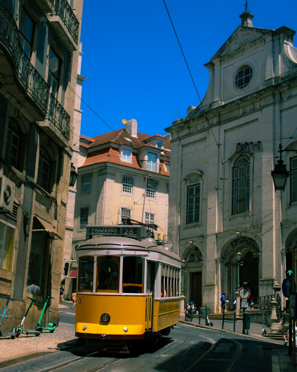 a yellow trolley car traveling down a street next to tall buildings