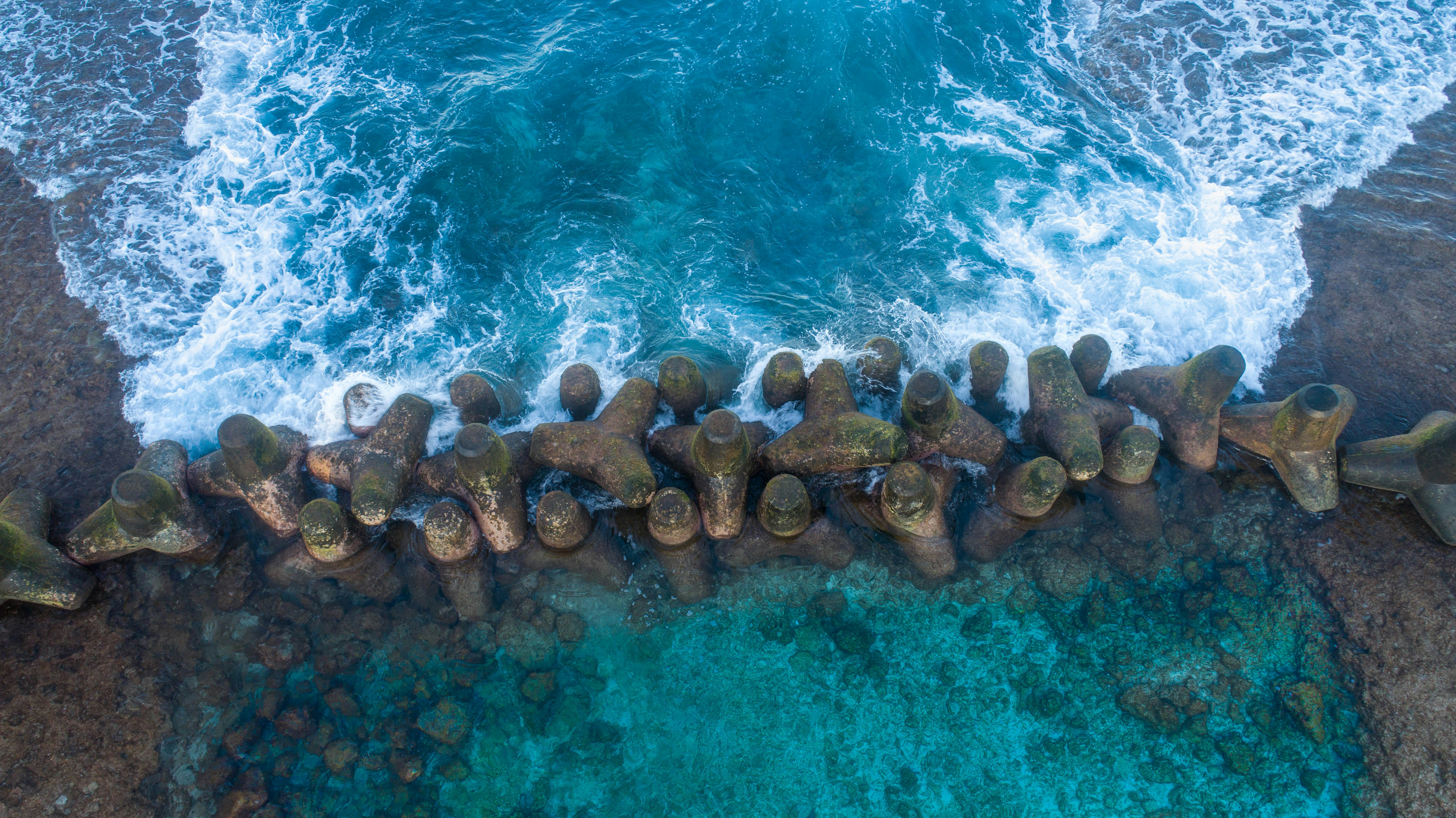 an aerial view of the ocean and rocks