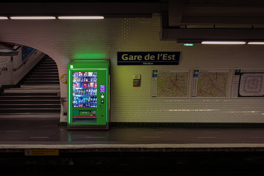 a green vending machine in a subway station