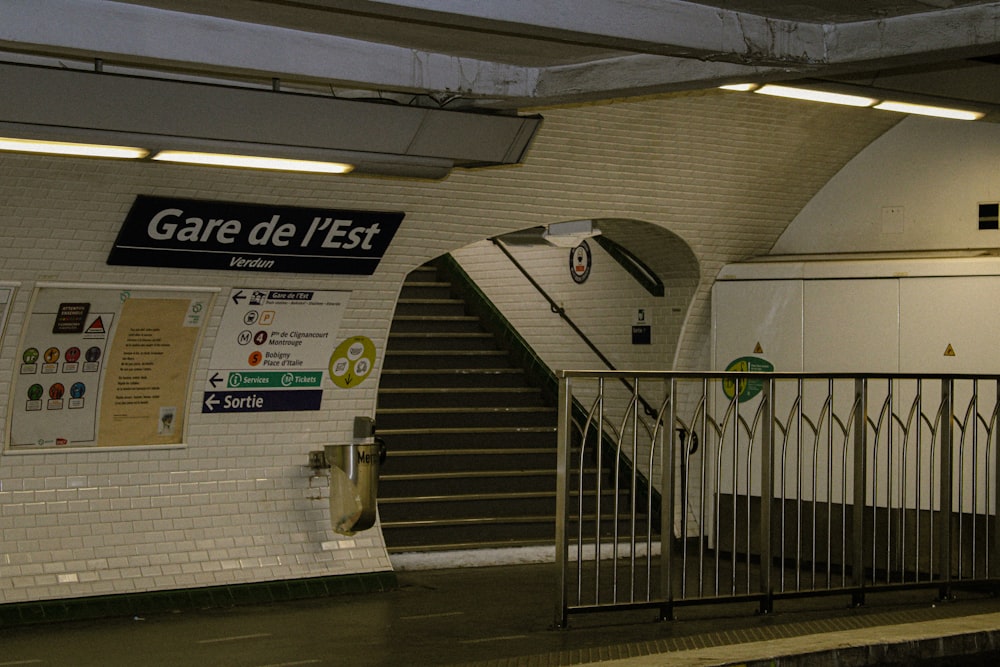 a subway station with a staircase and a sign on the wall