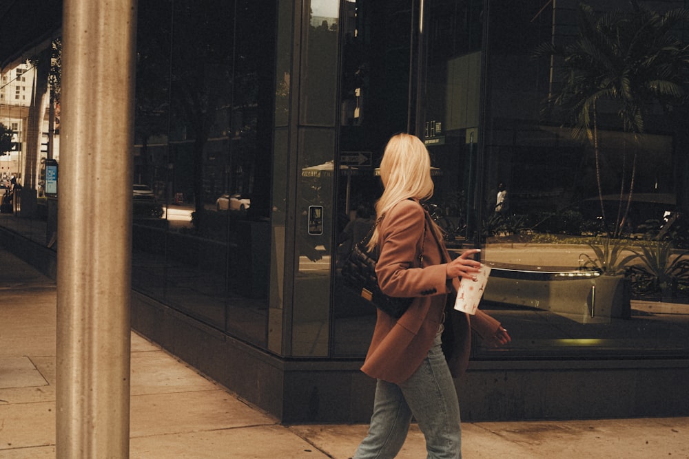 a woman walking down a sidewalk next to a tall building