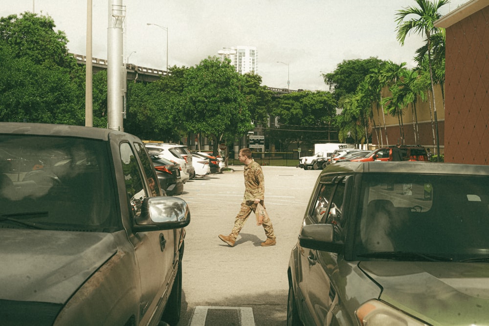 a man walking down a street next to parked cars