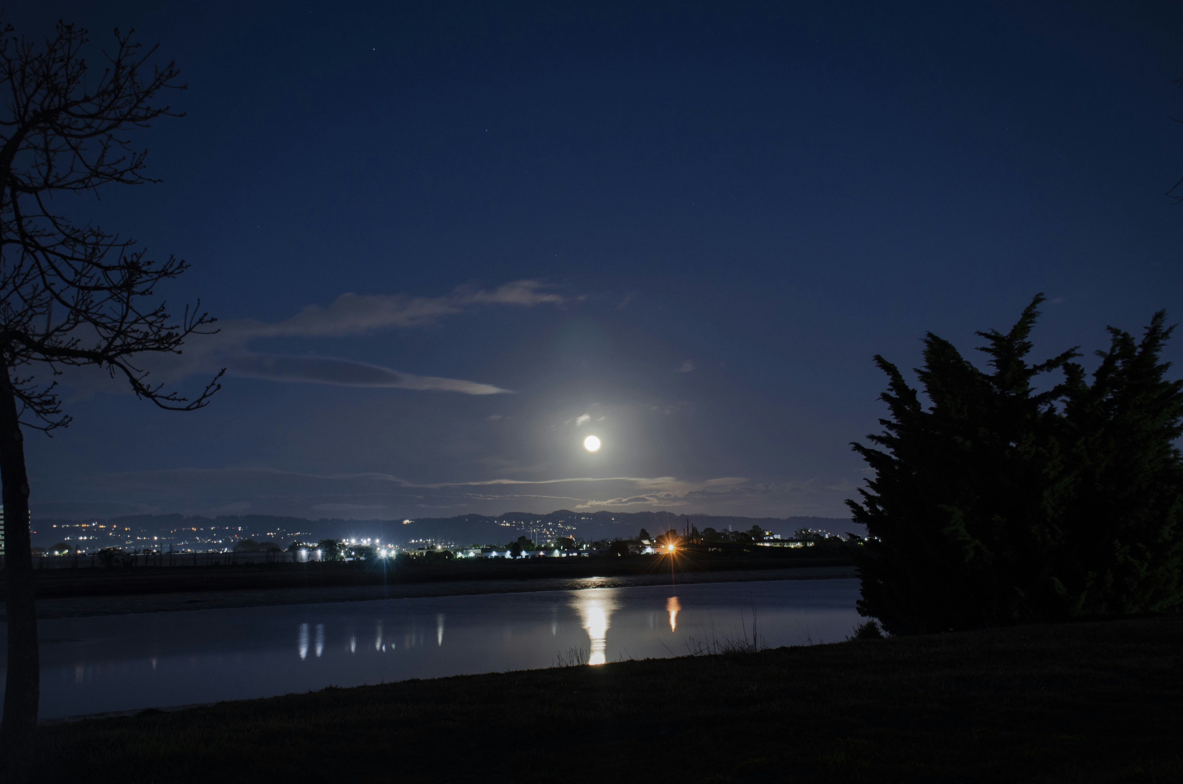 a full moon is seen over a lake at night, 