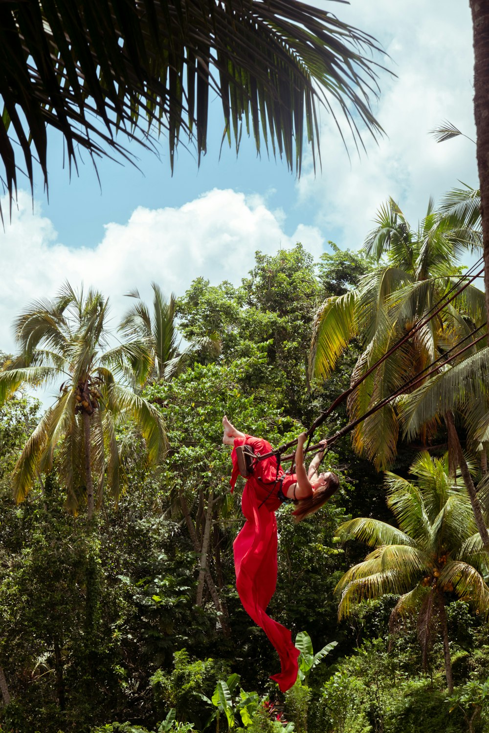 a woman in a red dress swinging from a rope
