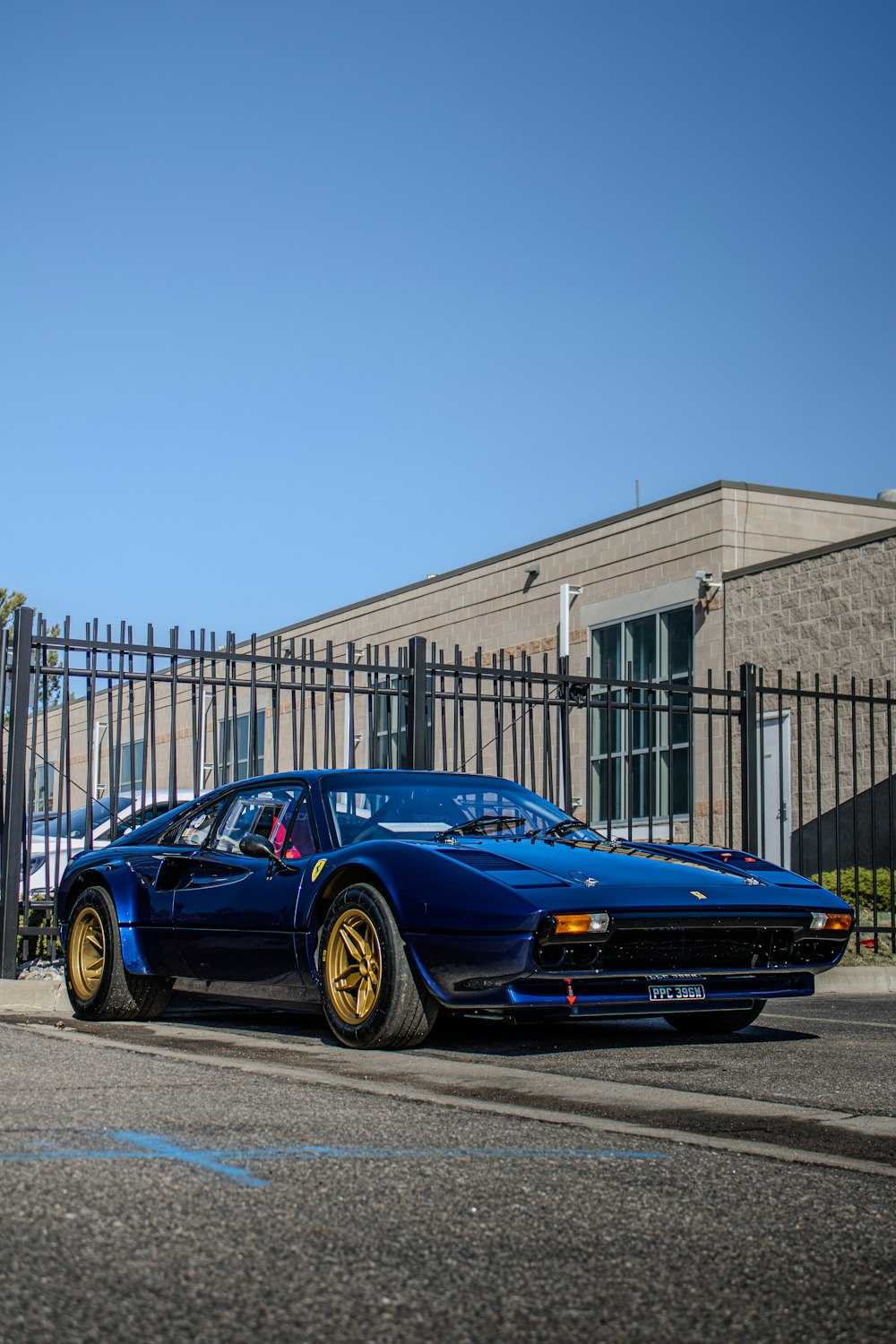 a blue sports car parked in front of a fence