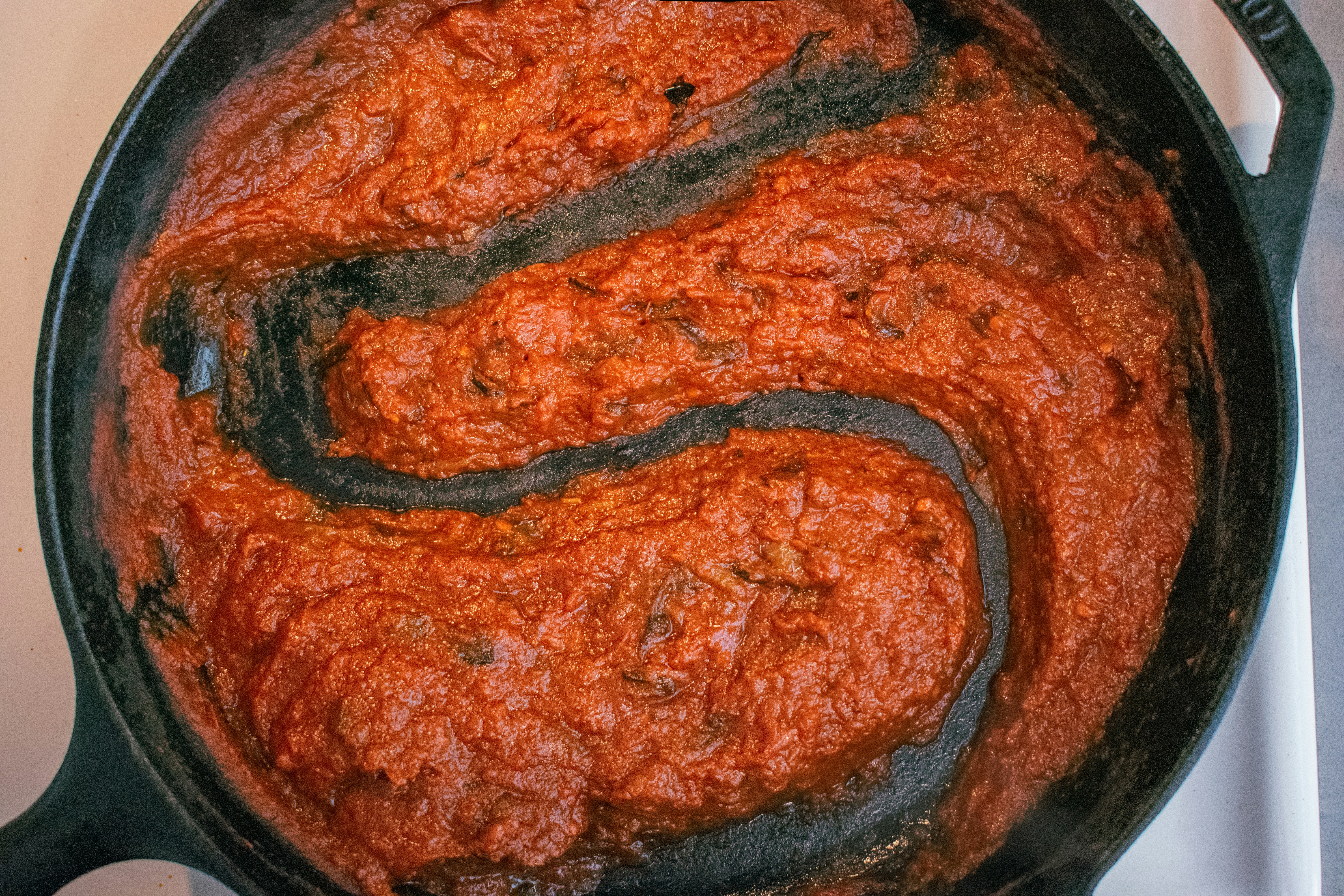 Rich red tomato sauce simmering in a copper pot with fresh basil leaves floating on top
