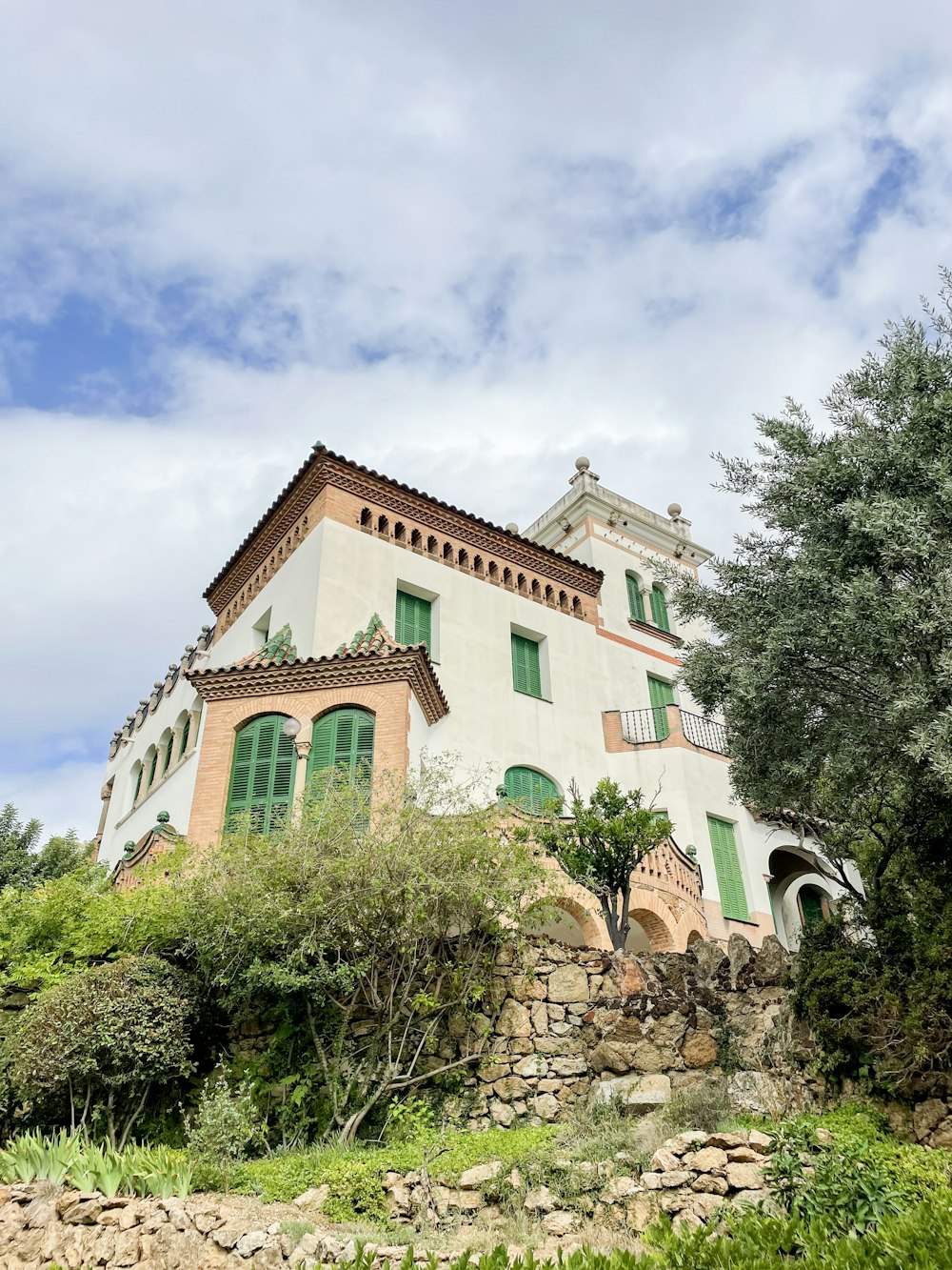 a large white house with green shutters on a hill