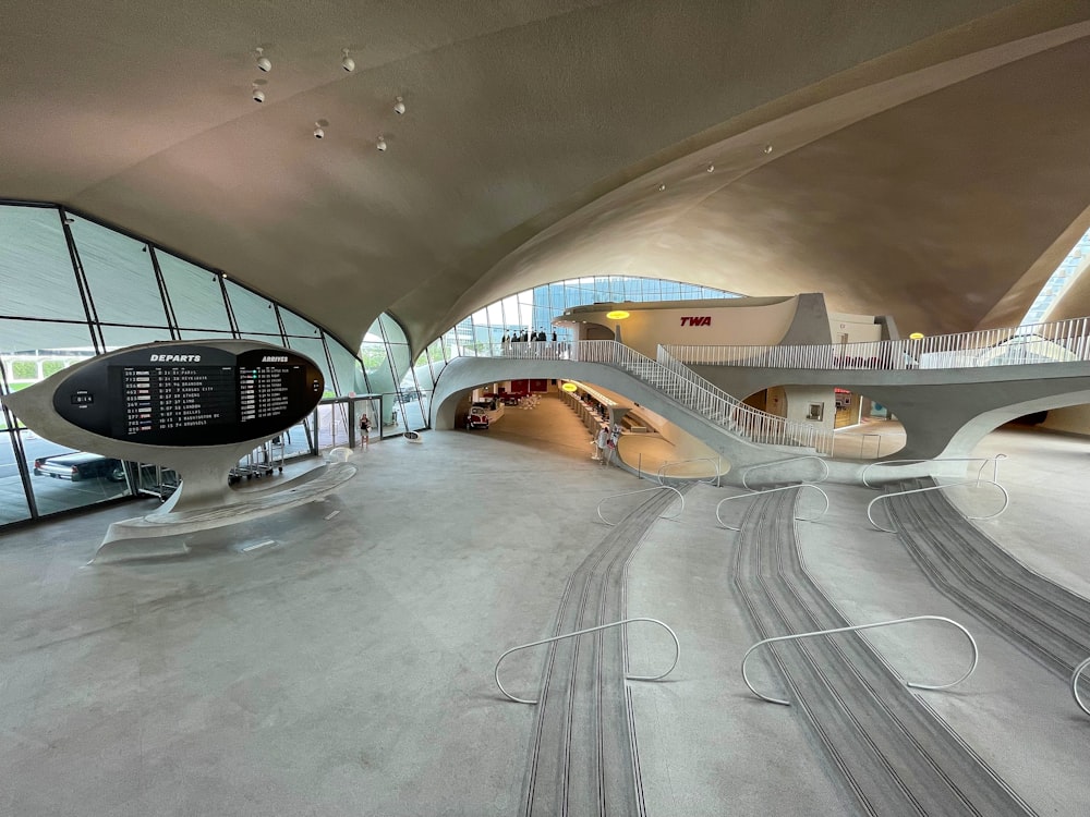 a curved walkway inside of a building with a clock on it