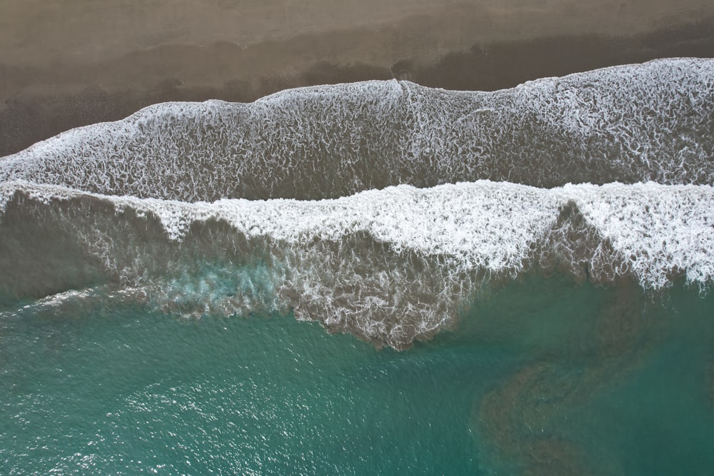 an aerial view of the ocean with waves crashing on the shore