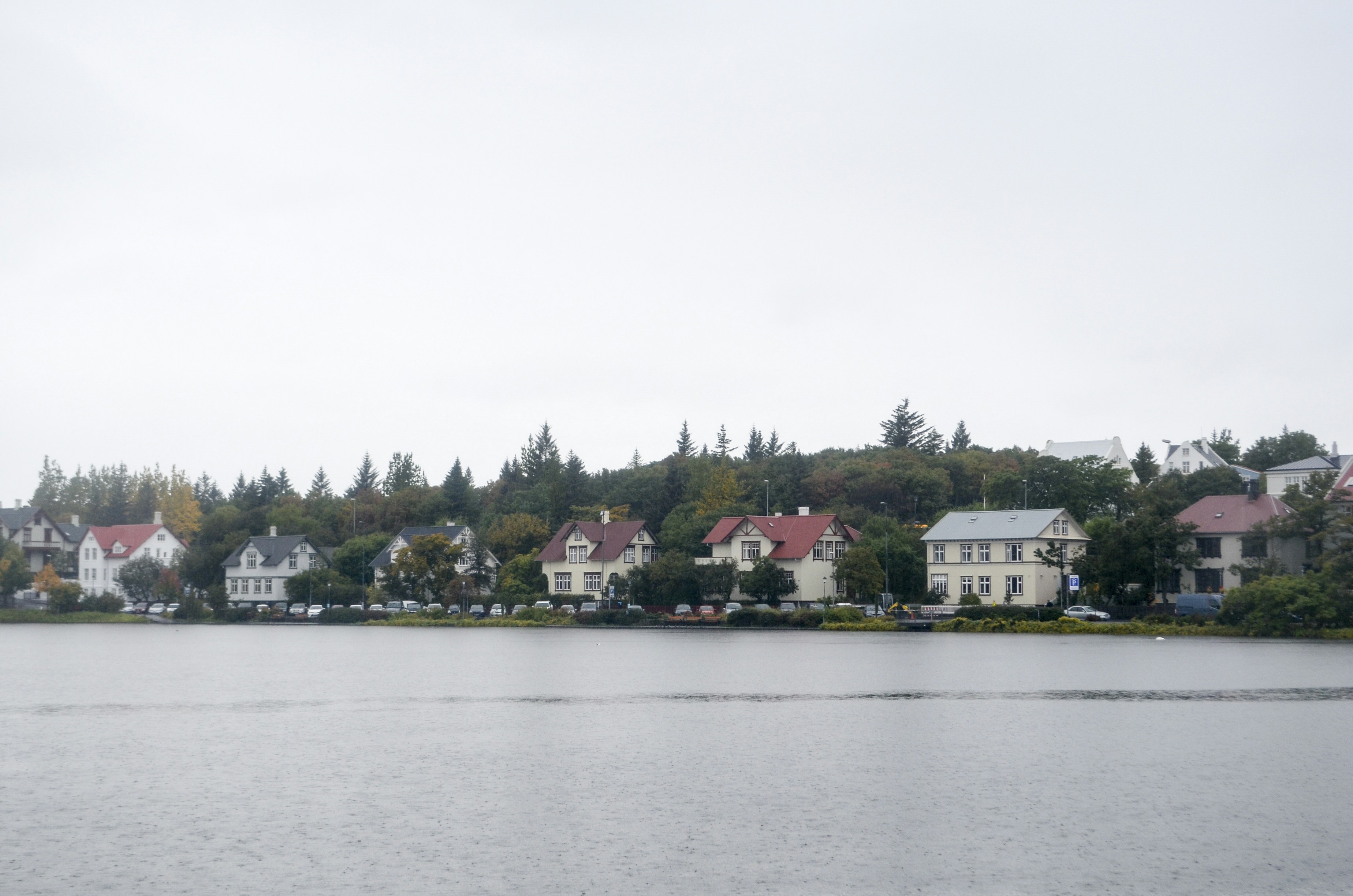 a body of water with houses on a hill in the background