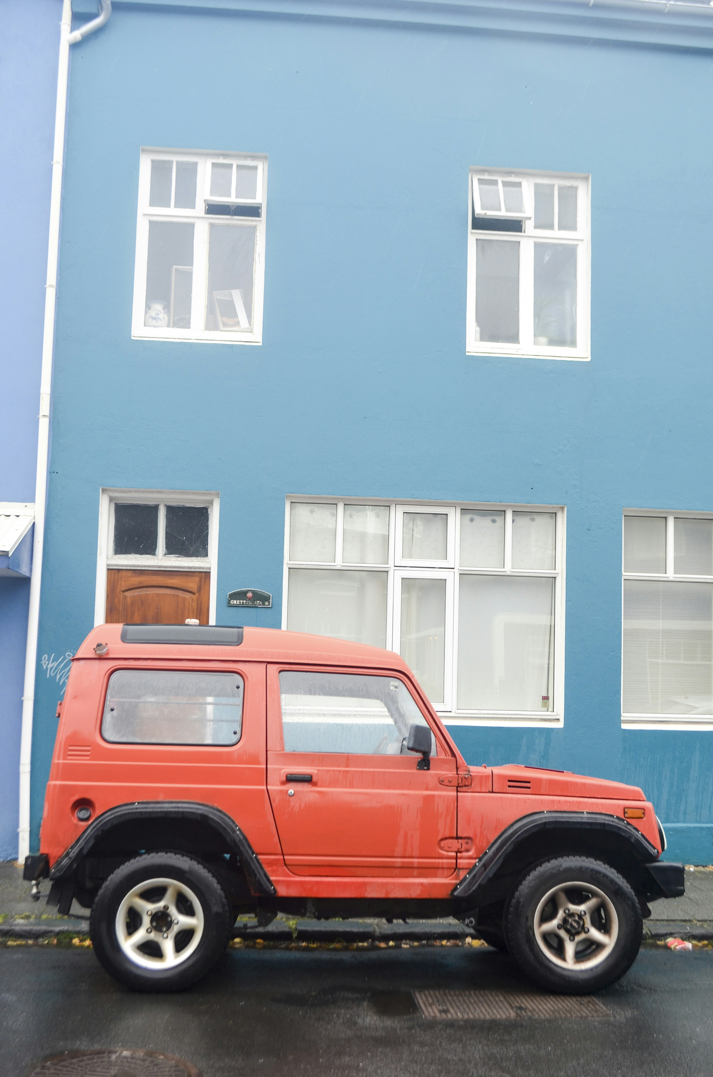 a red jeep parked in front of a blue building
