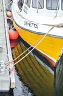 a yellow and white boat tied to a dock