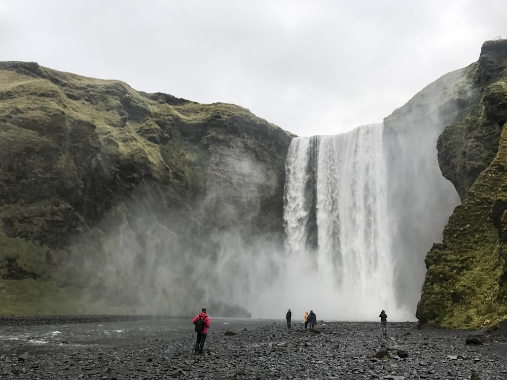 a group of people standing in front of a waterfall