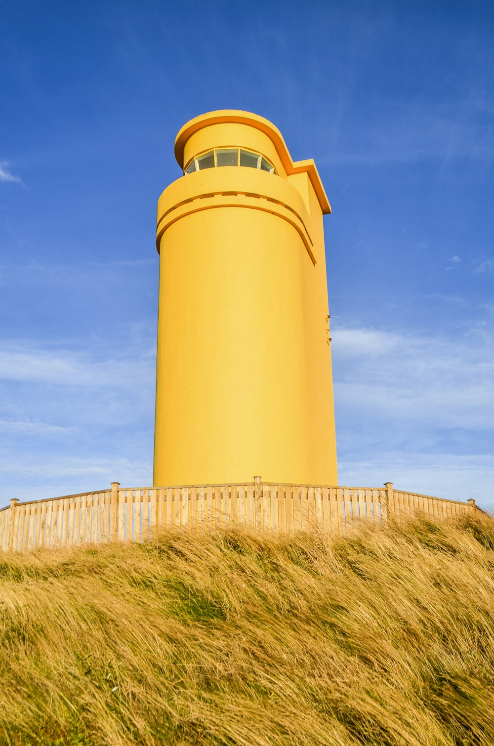 a tall yellow tower sitting on top of a grass covered hill
