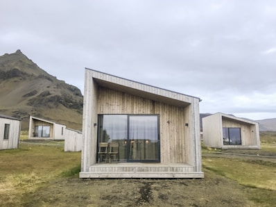 a couple of small houses sitting on top of a grass covered field