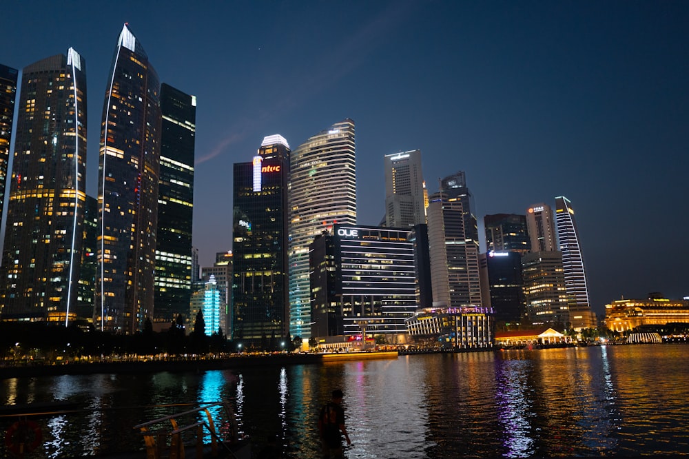 a city skyline at night with lights reflecting in the water