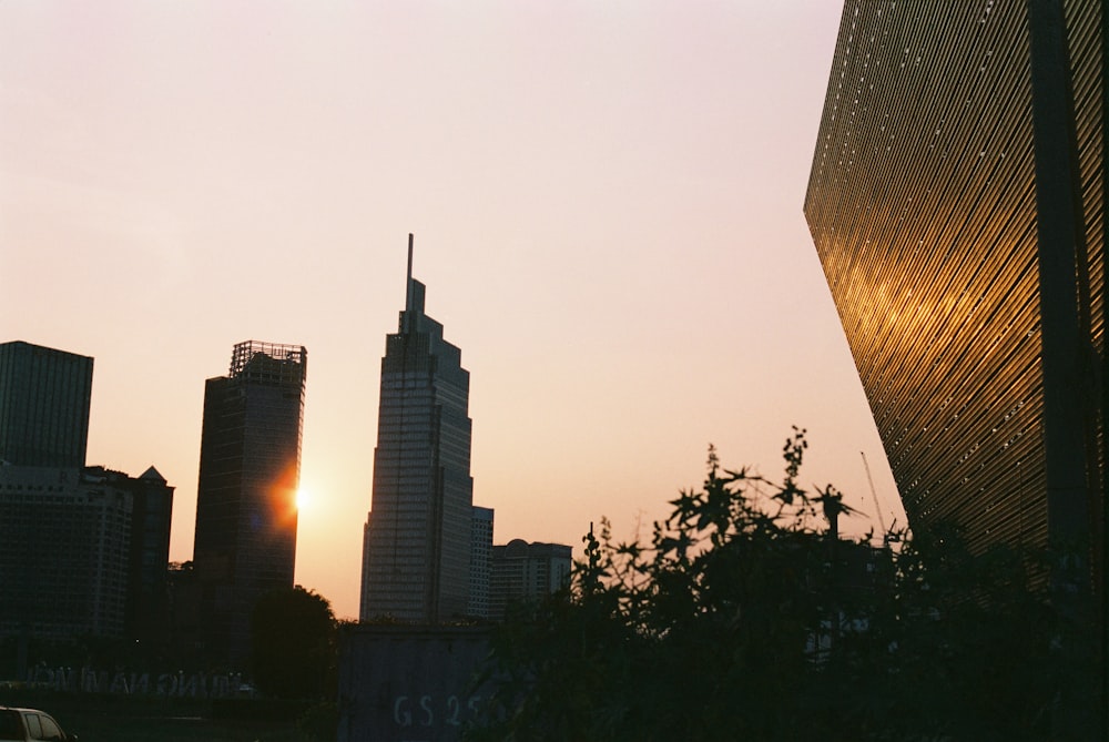 the sun is setting behind the tall buildings