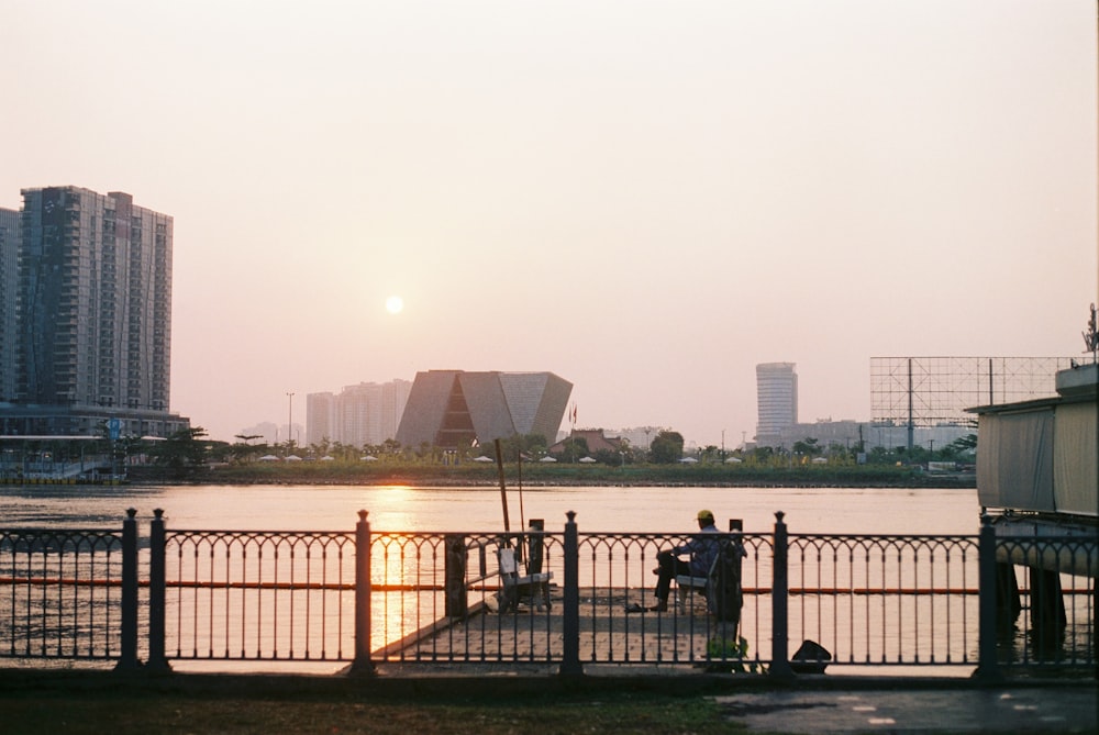 a couple of people sitting on a bench next to a body of water