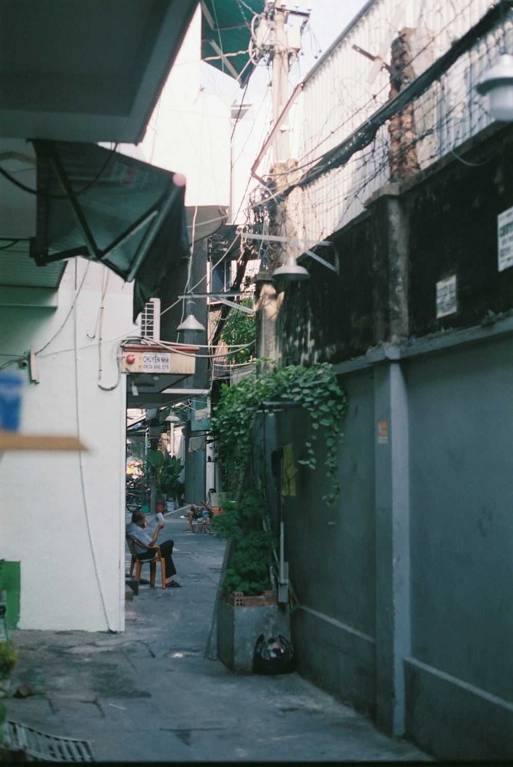 a narrow alley way with a person sitting on a bench
