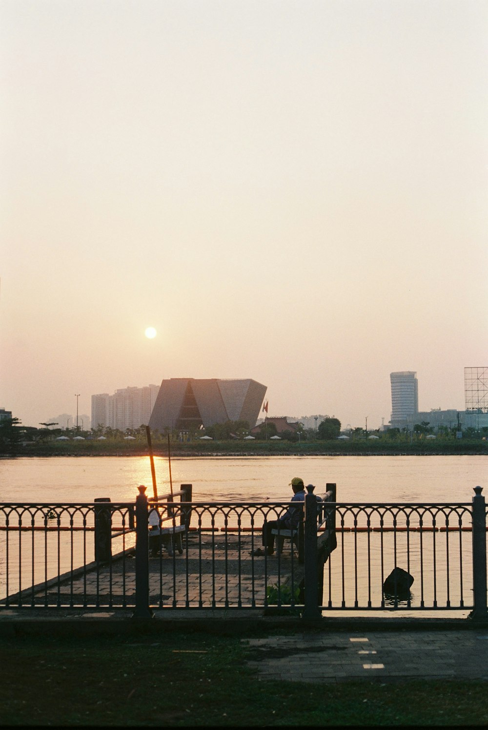 a person sitting on a bench next to a body of water