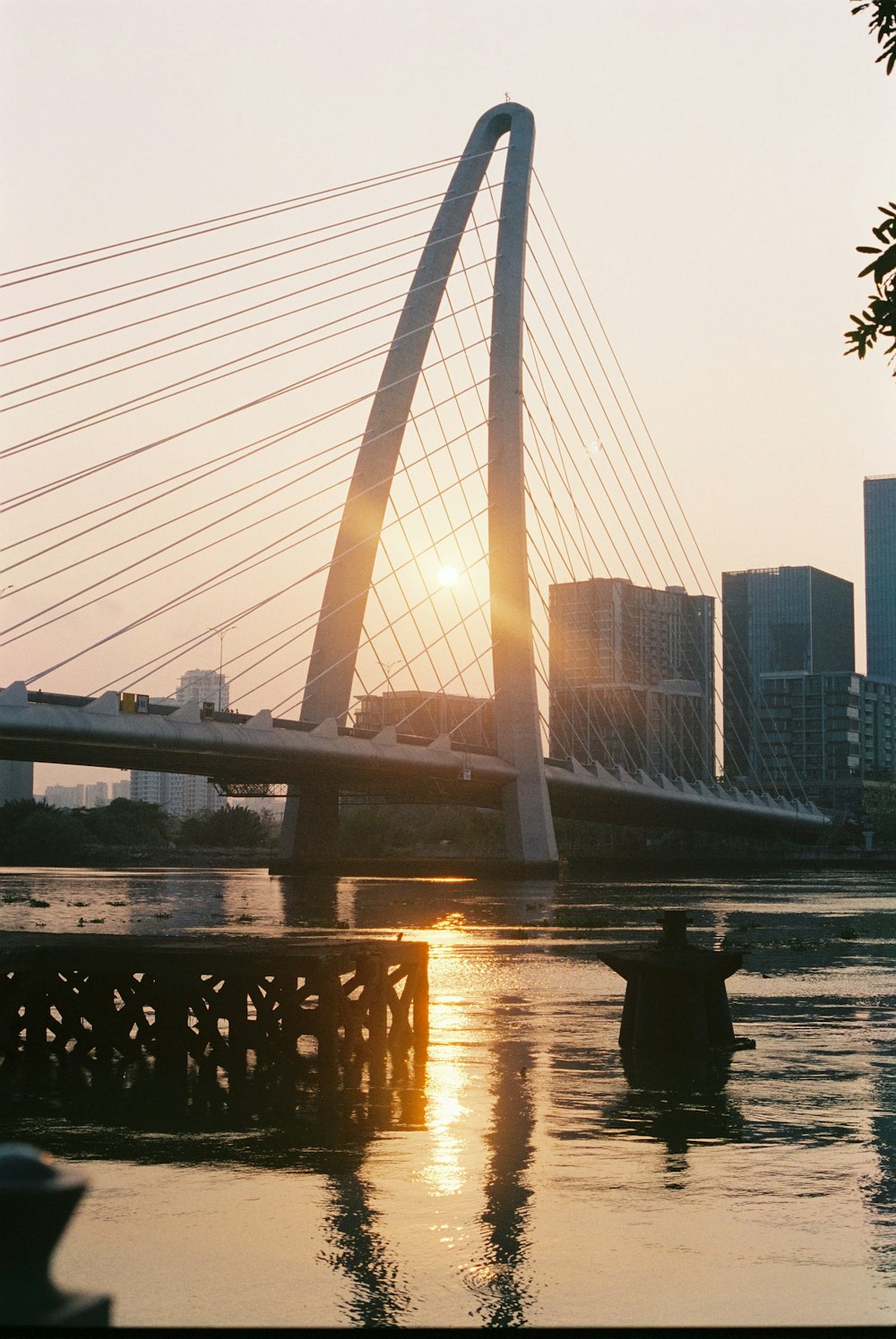 the sun is setting behind a bridge over a body of water