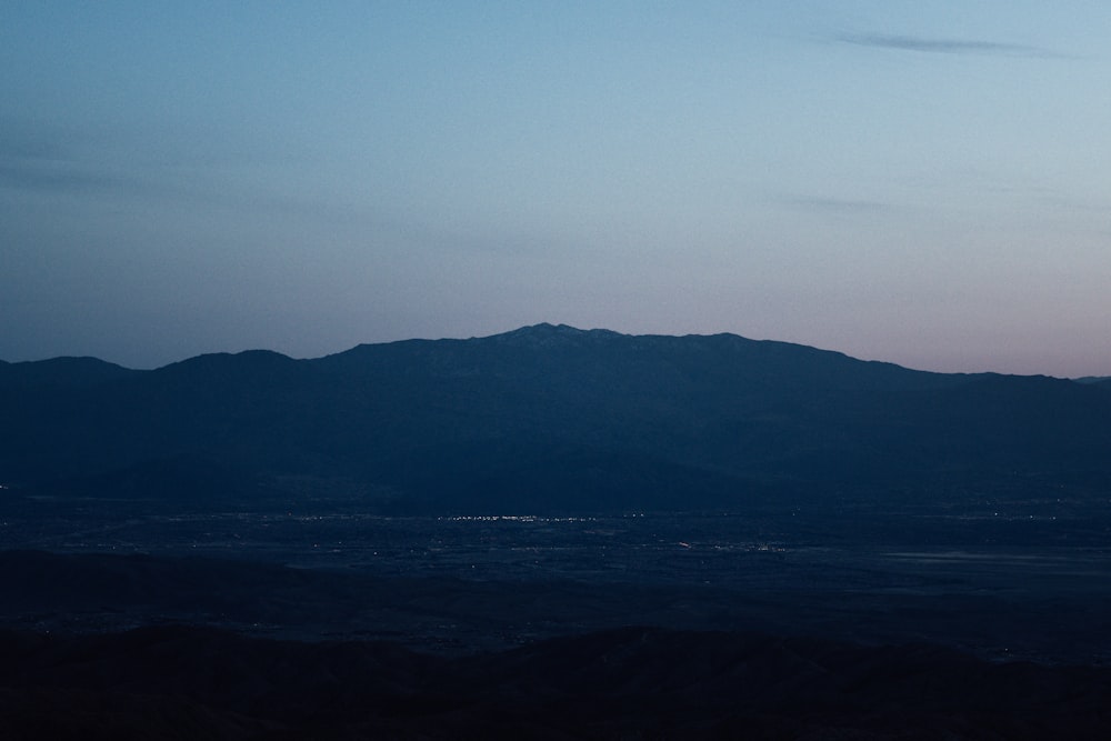 a plane flying over a mountain range at dusk