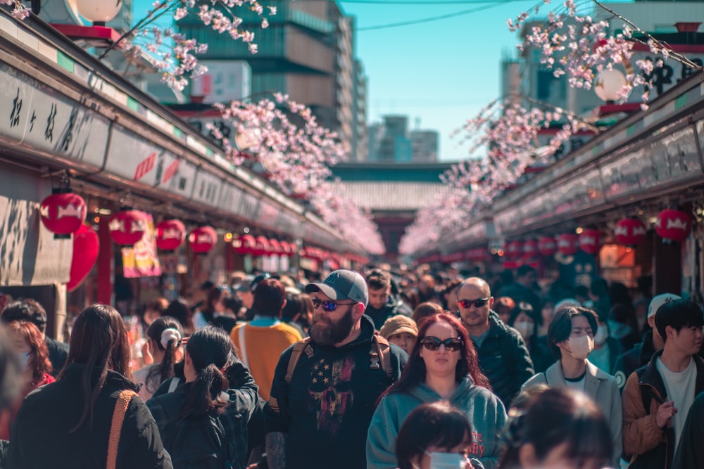 a crowd of people walking down a street next to tall buildings