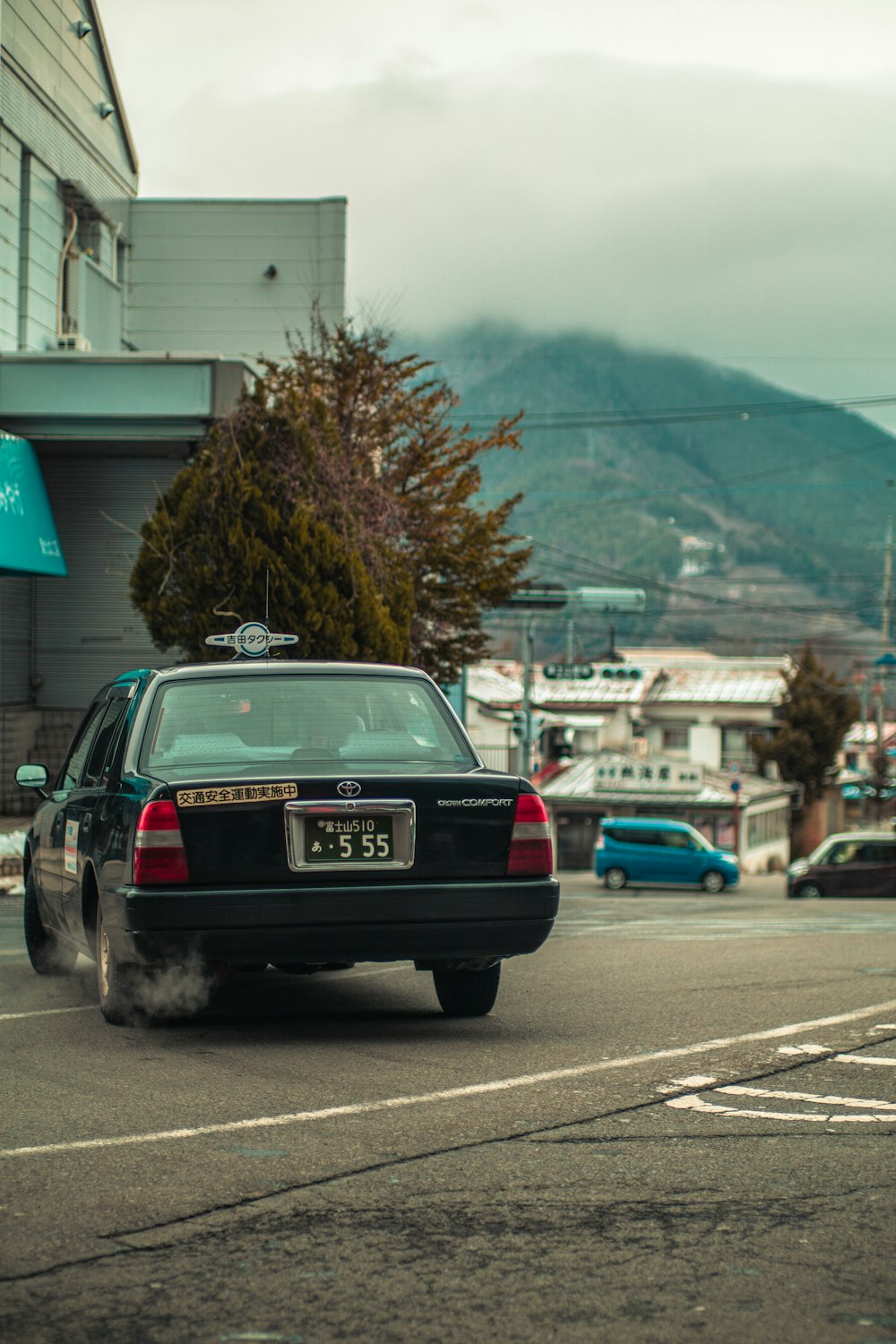 a black car driving down a street next to a tall building