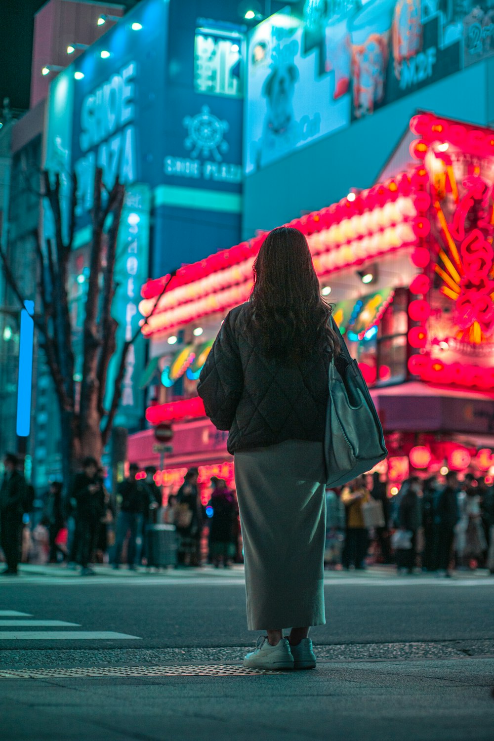 a woman standing on the side of a street at night