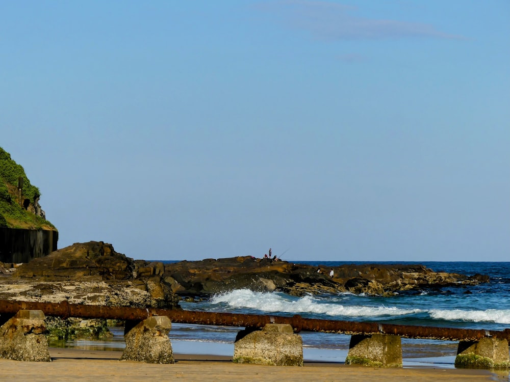 a bench sitting on top of a sandy beach next to the ocean