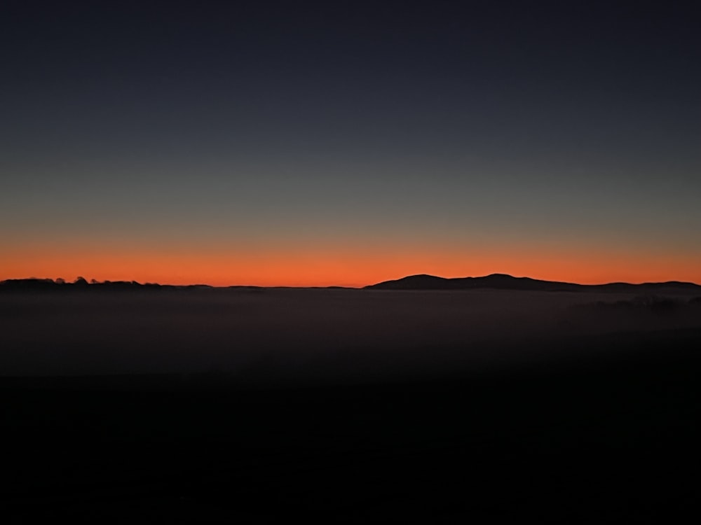 the sun is setting over a mountain range