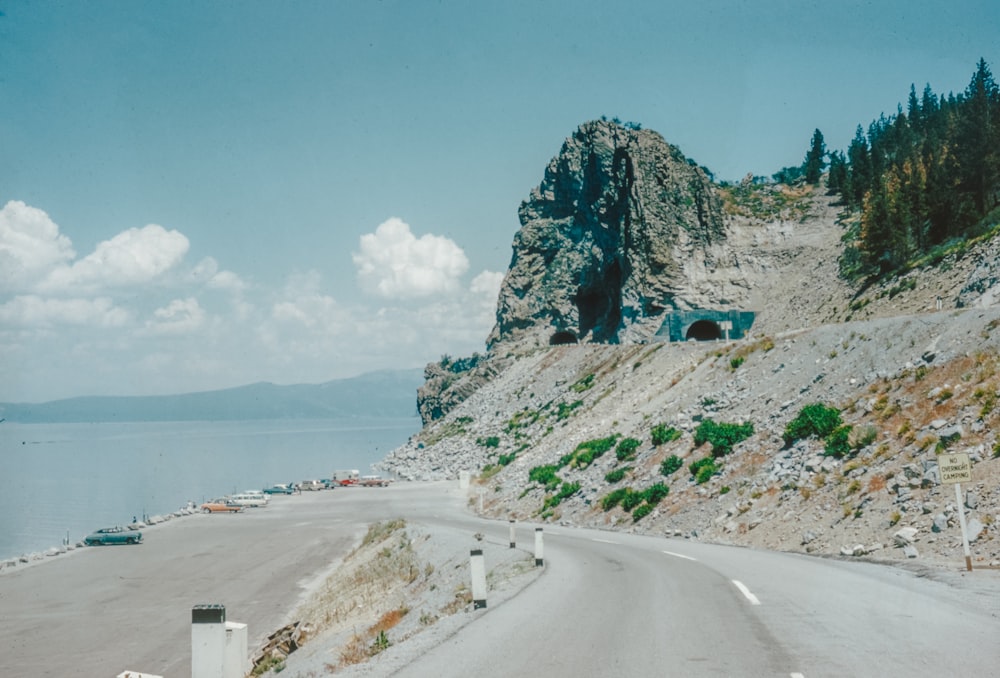 a car driving down a road next to a mountain