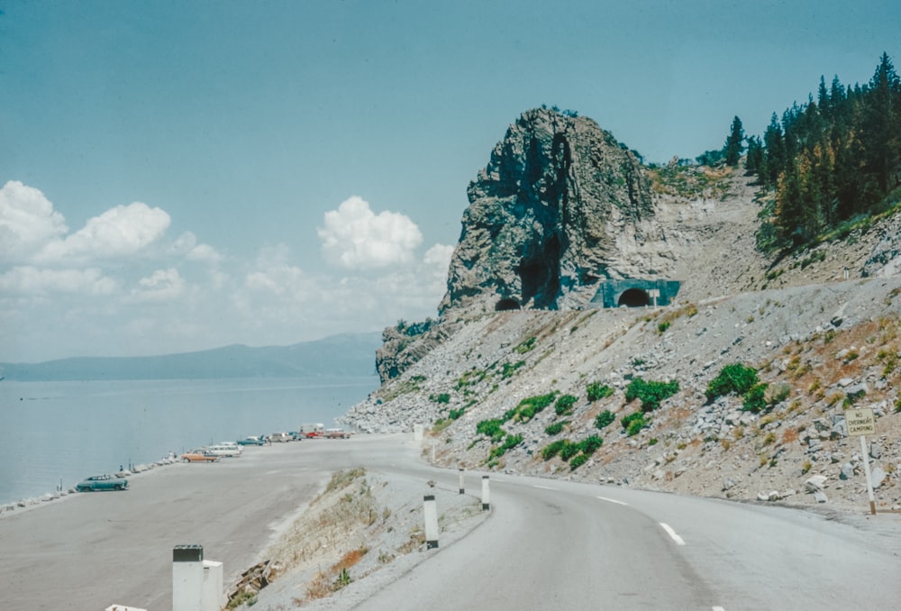 um carro dirigindo por uma estrada ao lado de uma montanha