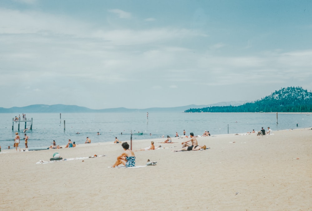 a group of people sitting on top of a sandy beach