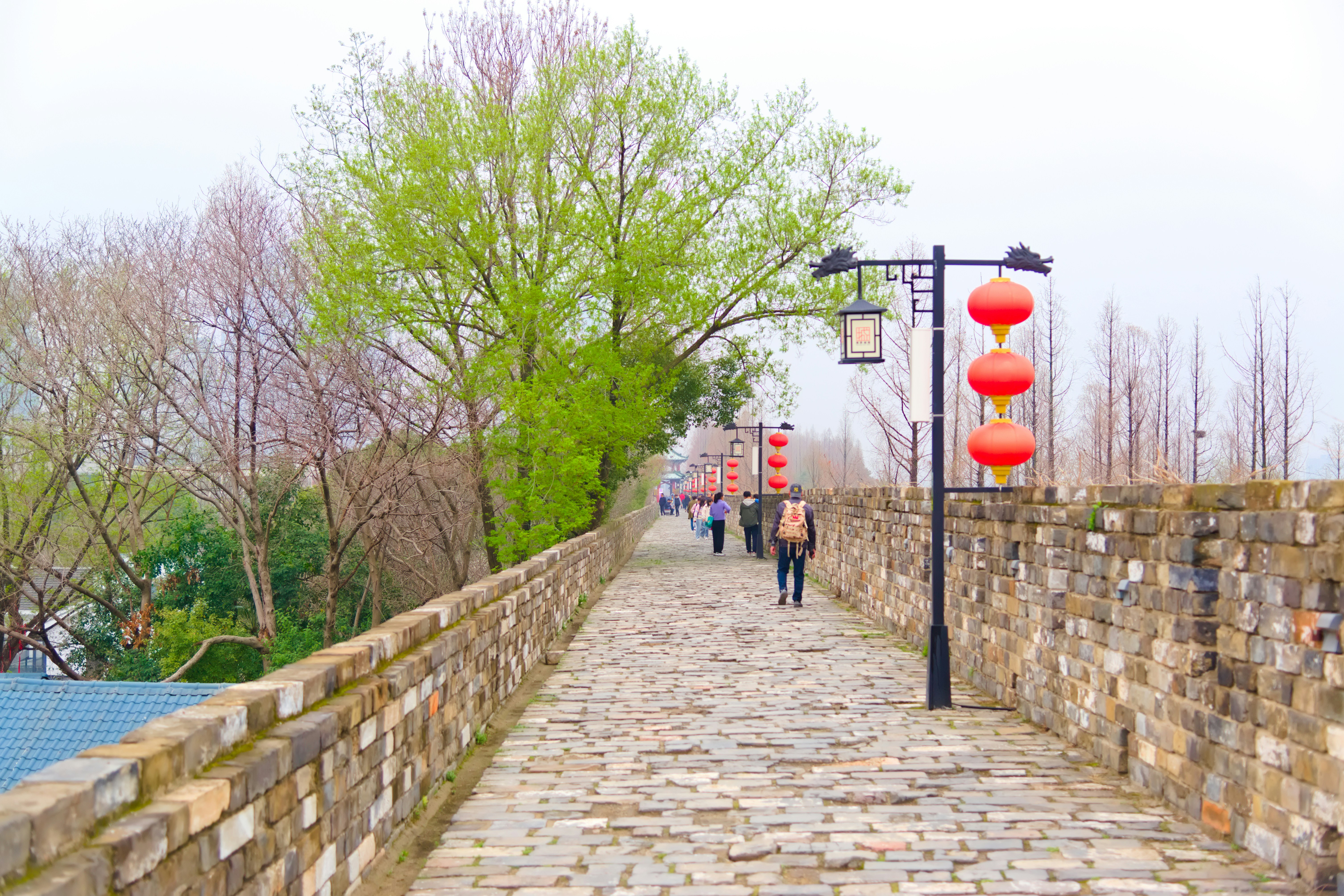 people walking down a brick path with red lanterns