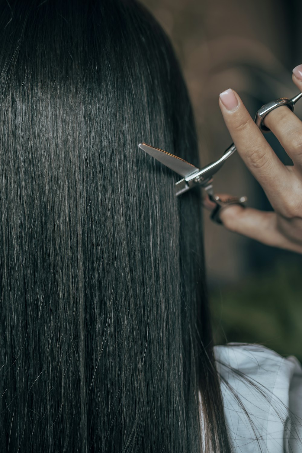a woman is cutting her hair with scissors