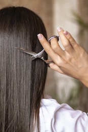 a woman cutting her hair with a pair of scissors