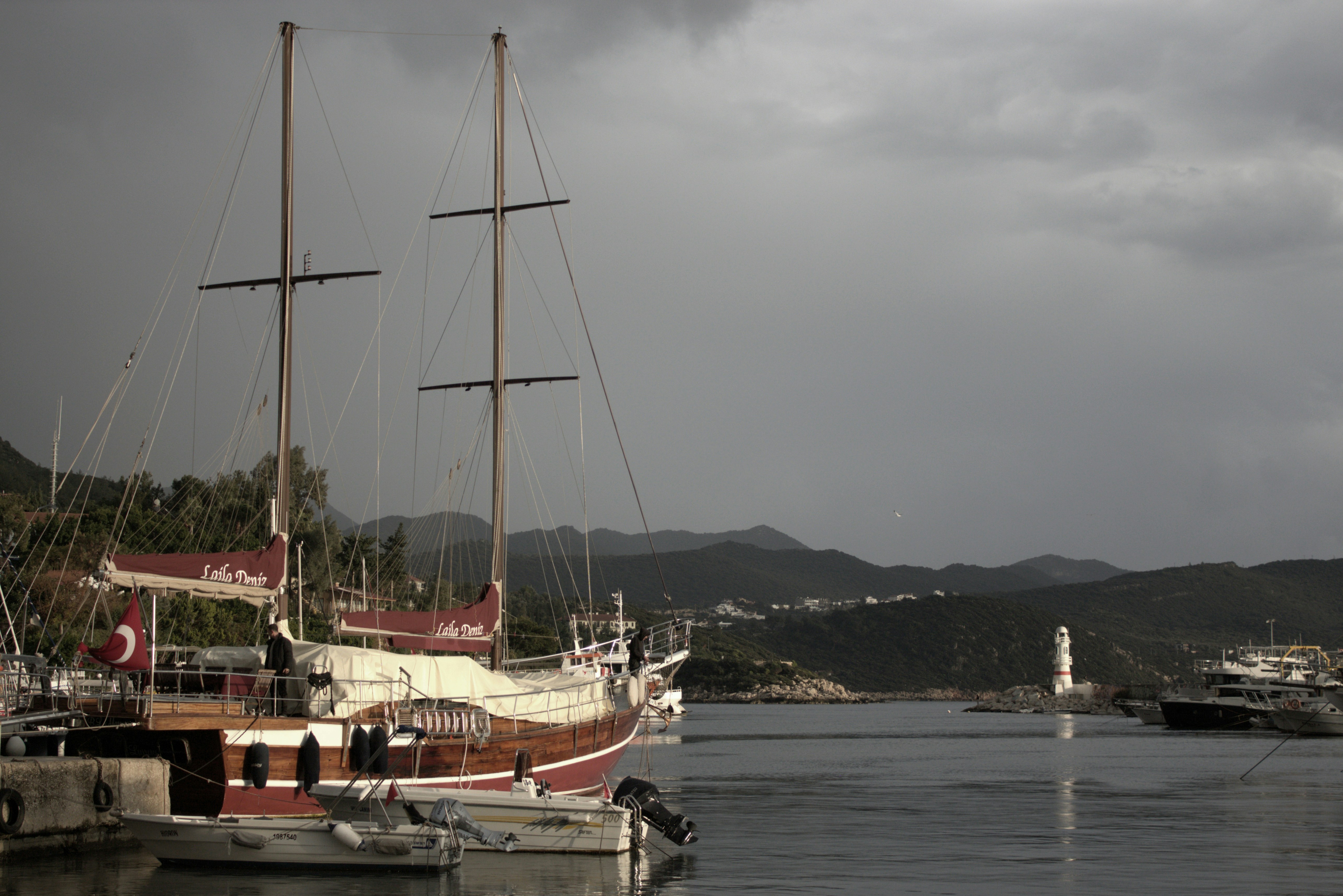 a sailboat docked in a harbor with mountains in the background